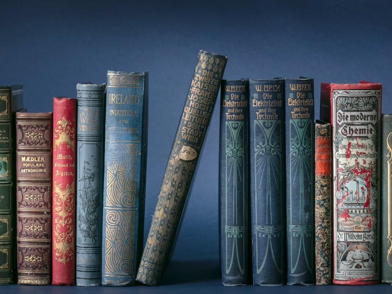 Colourful spines of historical publications against a blue background: 